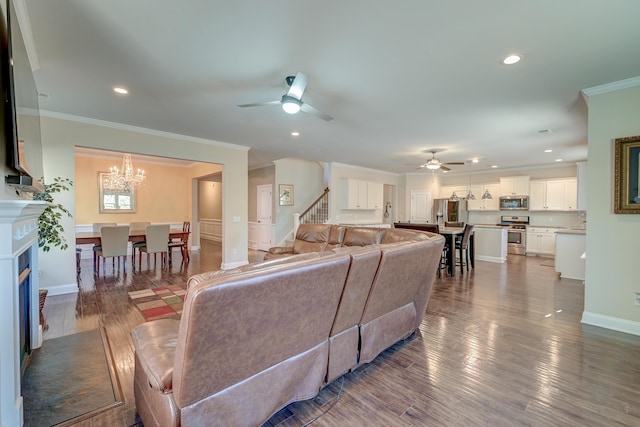 living room featuring ceiling fan with notable chandelier, dark hardwood / wood-style flooring, and crown molding