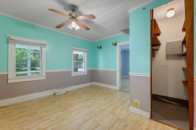 spare room with ceiling fan, visible vents, wood finished floors, baseboards, and ornamental molding