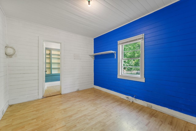 unfurnished bedroom with baseboards, wood walls, and wood finished floors