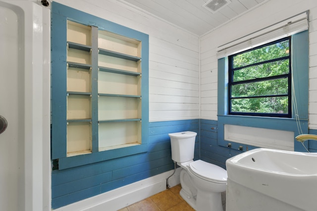 bathroom featuring wooden walls, a sink, tile patterned flooring, toilet, and visible vents