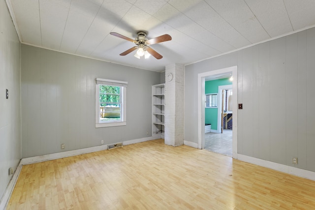 unfurnished bedroom featuring ceiling fan, visible vents, wood finished floors, baseboards, and ornamental molding