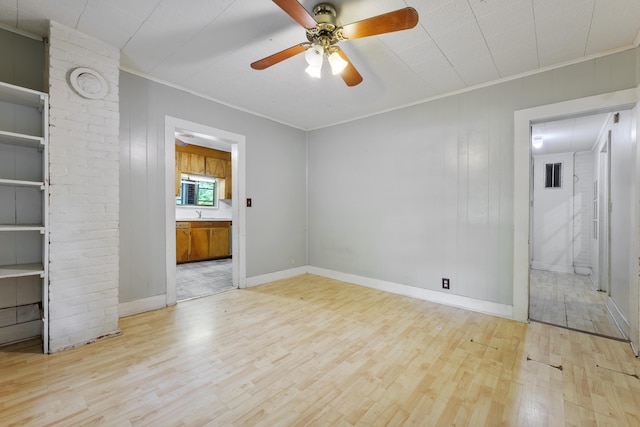 interior space with baseboards, crown molding, ceiling fan, and wood finished floors