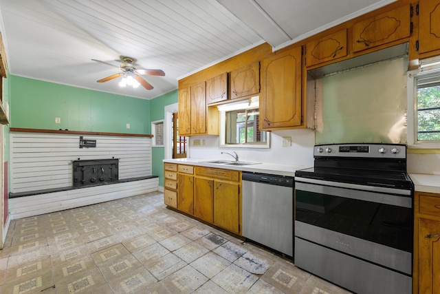 kitchen featuring brown cabinets, appliances with stainless steel finishes, a sink, light countertops, and a ceiling fan