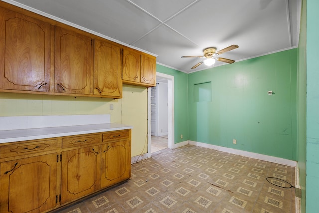 kitchen with baseboards, a ceiling fan, brown cabinets, and light countertops