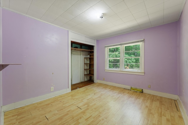 unfurnished bedroom with baseboards, wood finished floors, and a closet