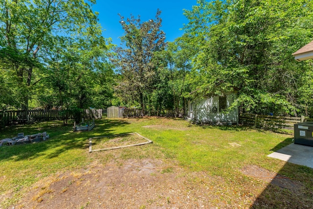 view of yard with a storage unit, a fenced backyard, and an outbuilding