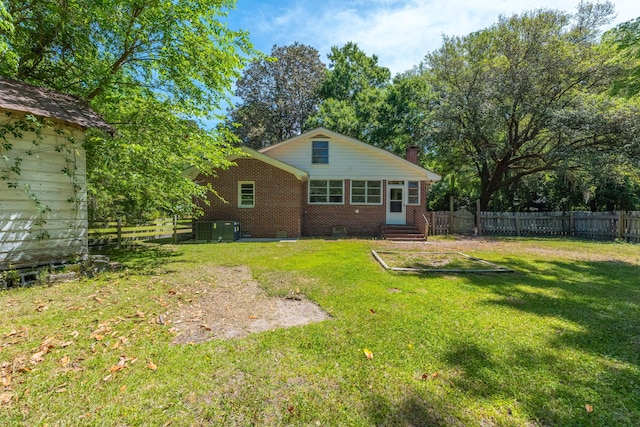 rear view of property featuring brick siding, a chimney, a fenced backyard, and entry steps