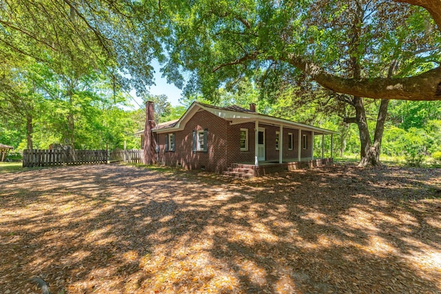 rear view of property featuring a porch, crawl space, a chimney, brick siding, and fence