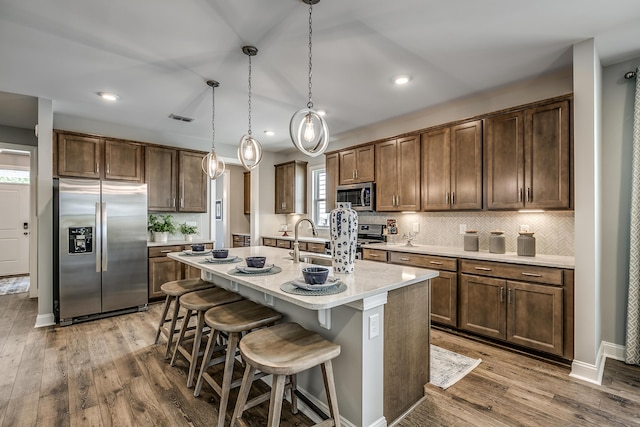 451 White Magnolia St, Moncks Corner, SC 29461 - kitchen featuring stainless steel appliances, a sink, wood finished floors, decorative backsplash, and light countertops