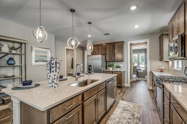 451 White Magnolia St, Moncks Corner, SC 29461 - kitchen featuring appliances with stainless steel finishes, a sink, dark wood finished floors, a center island with sink, and light stone countertops