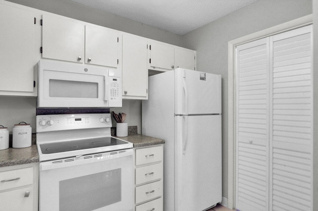 kitchen with white appliances, a textured ceiling, and white cabinets