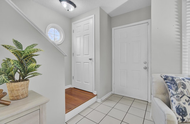 foyer entrance featuring a textured ceiling and light tile patterned flooring