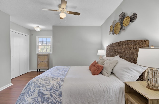 bedroom with ceiling fan, dark wood-type flooring, a textured ceiling, and a closet