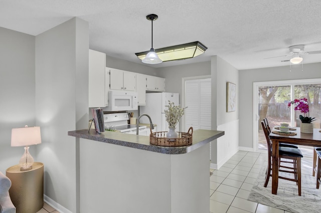 kitchen with white cabinetry, hanging light fixtures, a textured ceiling, kitchen peninsula, and white appliances