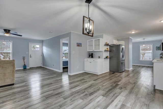 kitchen featuring white cabinets, pendant lighting, stainless steel fridge, and light hardwood / wood-style floors