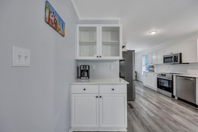 kitchen with white cabinetry, crown molding, light hardwood / wood-style flooring, and stainless steel appliances