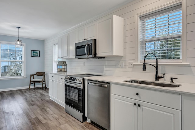 kitchen with white cabinetry, appliances with stainless steel finishes, sink, and pendant lighting