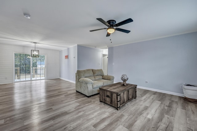 living room with ornamental molding, ceiling fan with notable chandelier, and light wood-type flooring