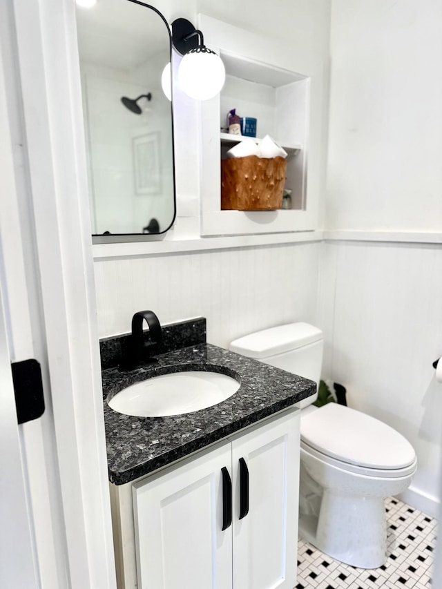 bathroom with tile patterned floors, toilet, vanity, and wooden walls