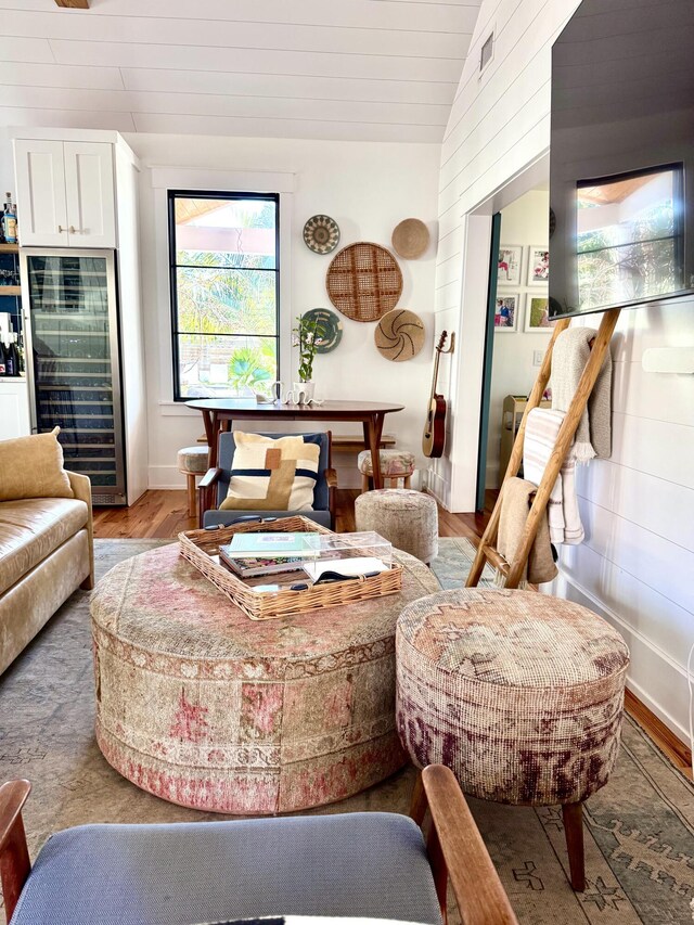 living room featuring wine cooler, hardwood / wood-style floors, and vaulted ceiling