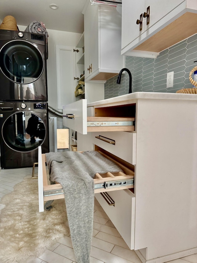 washroom with cabinets and stacked washer / dryer