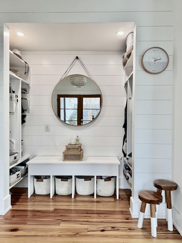 mudroom with hardwood / wood-style floors and wooden walls