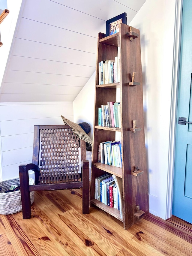 sitting room featuring lofted ceiling, wood walls, and light hardwood / wood-style flooring