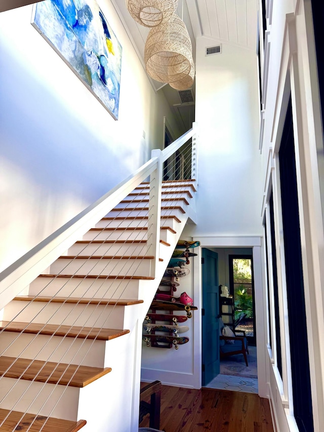 stairs featuring a towering ceiling and hardwood / wood-style flooring