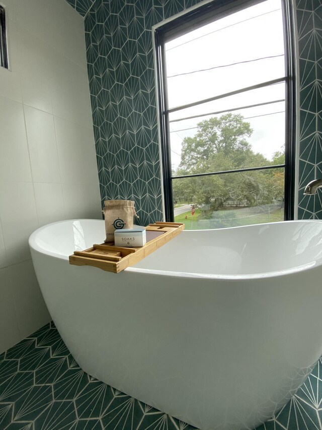 bathroom featuring tile patterned flooring, tile walls, and a tub