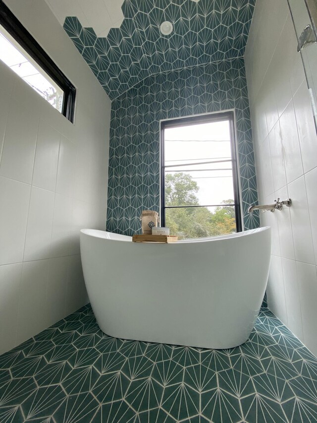 bathroom with tile walls, tile patterned flooring, and a washtub