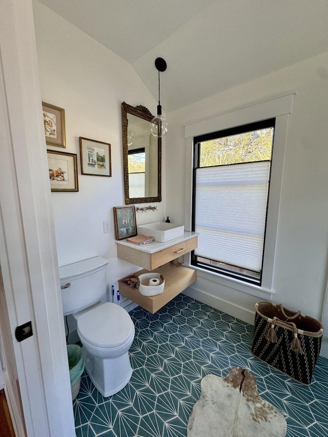 bathroom featuring toilet, lofted ceiling, and sink