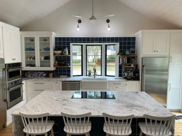 kitchen featuring a kitchen bar, white cabinets, light stone counters, and appliances with stainless steel finishes