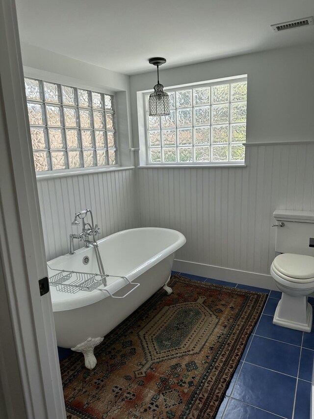 bathroom with toilet, tile patterned flooring, and a washtub