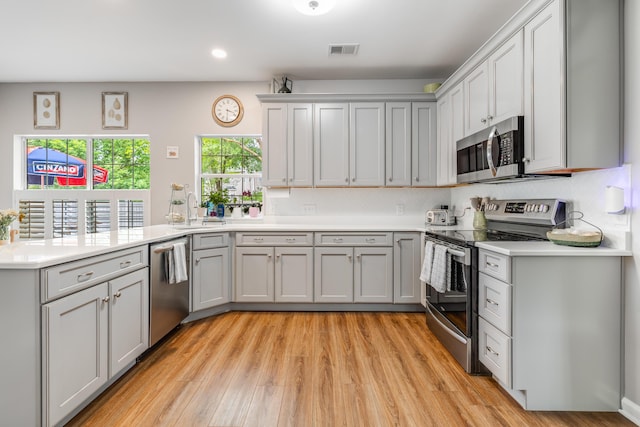261 Mossy Oak Way, Mount Pleasant, SC 29464 - kitchen featuring stainless steel appliances, a peninsula, a sink, light wood-type flooring, and light countertops