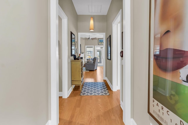 corridor featuring wood finished floors, visible vents, and baseboards