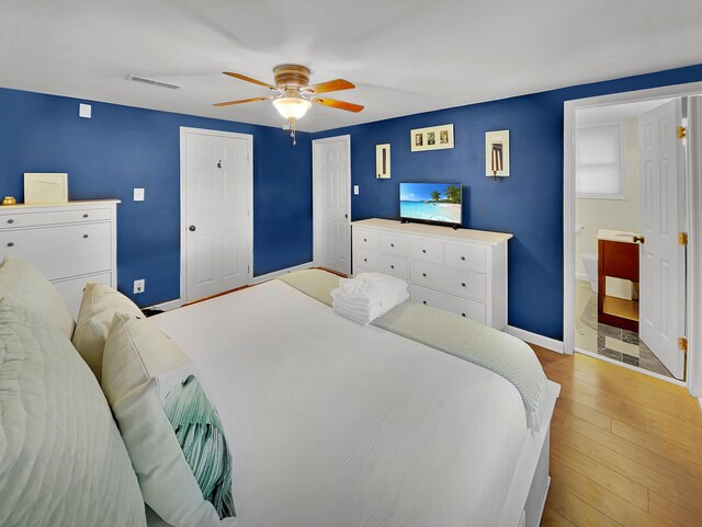 bedroom featuring hardwood / wood-style floors, baseboards, ceiling fan, and ensuite bathroom
