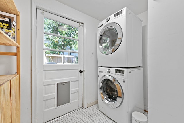 laundry room with stacked washing machine and dryer and light tile patterned floors