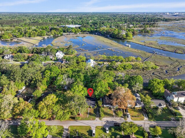 aerial view of property and surrounding area with a heavily wooded area and a nearby body of water