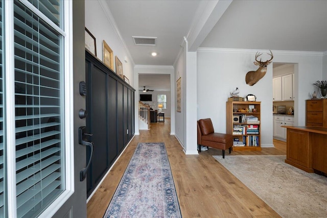 foyer entrance featuring visible vents, light wood-style flooring, baseboards, and ornamental molding