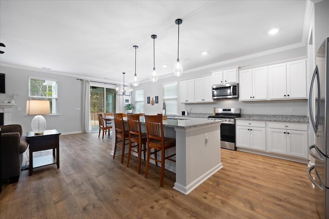 kitchen featuring a center island, light wood-style flooring, stainless steel appliances, and crown molding