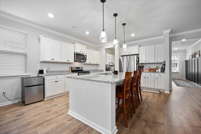 kitchen with visible vents, a breakfast bar, a sink, stainless steel appliances, and light wood finished floors