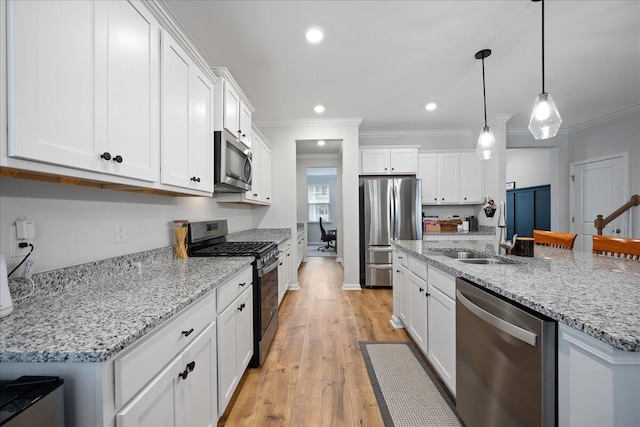 kitchen featuring light wood finished floors, crown molding, pendant lighting, stainless steel appliances, and white cabinetry