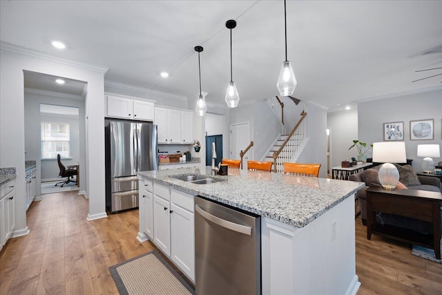 kitchen featuring open floor plan, a center island with sink, light wood-type flooring, stainless steel appliances, and a sink