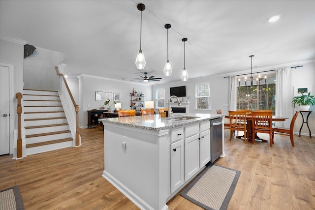 kitchen featuring crown molding, white cabinets, light wood finished floors, and a sink