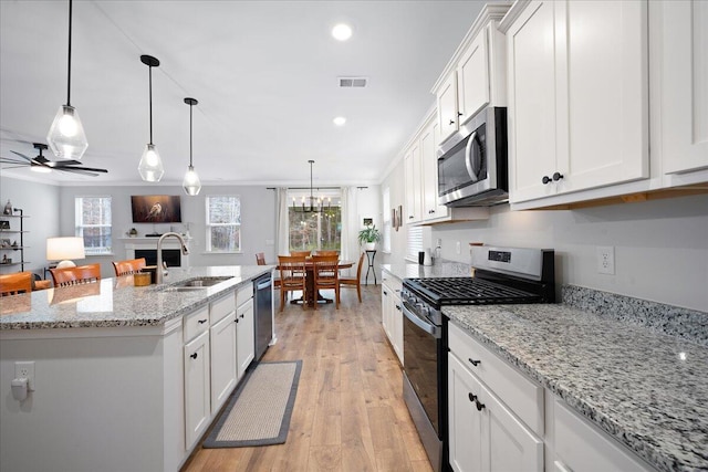 kitchen with visible vents, appliances with stainless steel finishes, a fireplace, white cabinetry, and a sink