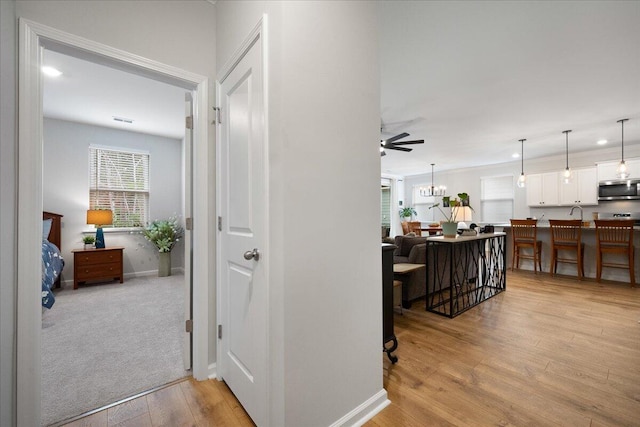 hall with light wood finished floors, visible vents, baseboards, a chandelier, and recessed lighting