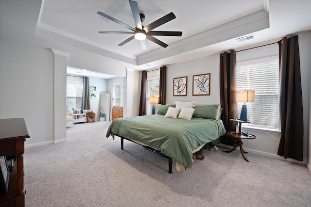 carpeted bedroom with a tray ceiling, multiple windows, and ornamental molding