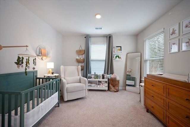 bedroom featuring visible vents, multiple windows, light colored carpet, and a crib