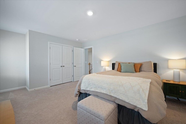 bedroom featuring light colored carpet, baseboards, and a closet