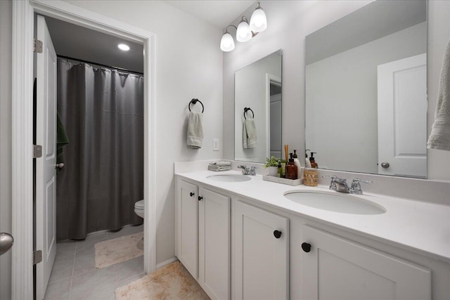 full bathroom featuring tile patterned floors, double vanity, toilet, and a sink